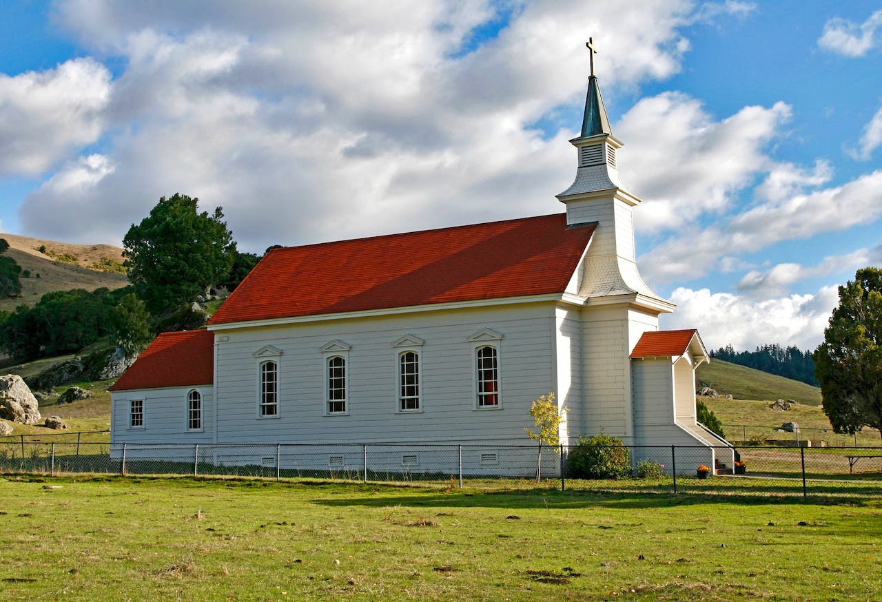 Red and White Concrete Church on Green Grass Field<br />
